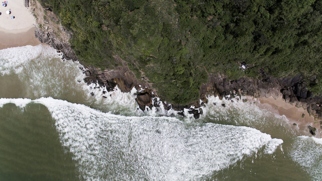 Top down aerial view of waves breaking on rocky shore and Atlantic Forest at Canto do Morcego, Praia Brava, Itajai, Brazil