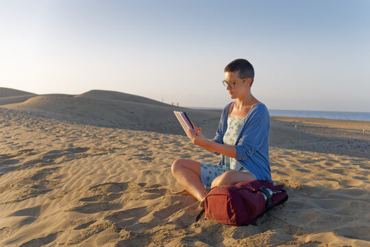 Woman using tablet during outdoor work break on sand dunes
