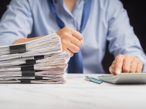 Stressed businessperson calculating company revenue with calculator 