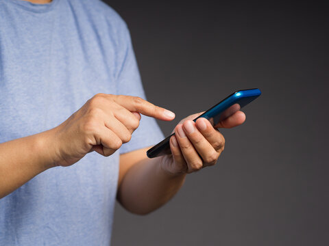 Close-up of hands using smartphone against dark background 