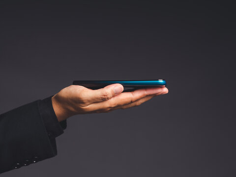 Smartphone resting on businessperson's palm against dark background
