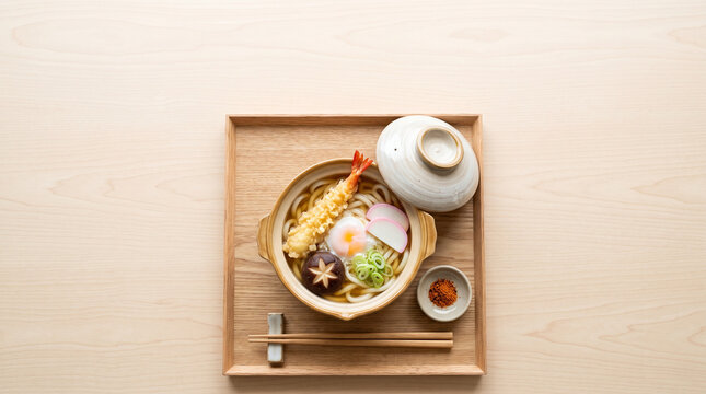 Overhead view of nabeyaki udon on a wooden tray with chopsticks