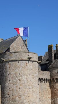 Close view of historic abbey walls with French flag waving in coastal wind, symbolizing national heritage, cultural pride and timeless identity of France