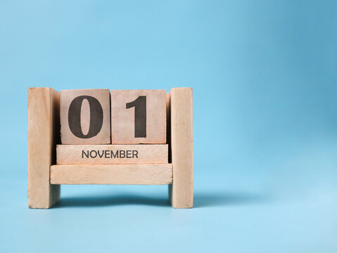 A wooden block calendar for November 1st on a light blue background.