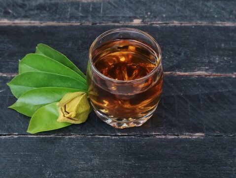 Glass of healthy soursop leaves boiled water with fresh green leaves on dark rustic wooden background. Natural herbal remedy, alternative medicine, organic wellness drink concept