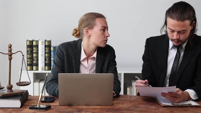 Professional lawyers collaborating on a legal case while consulting a laptop and signing documents in a modern office