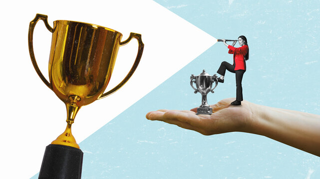 A young woman with a telescope stands on on the small trophy, and I'm looking for a larger prize cup. Consolation prize award and victory concept.