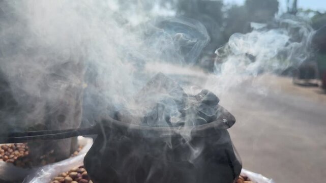 Street vendor heating peanuts in a roadside roasting pan in India, preparing a popular traditional snack for customers in a bustling street setting