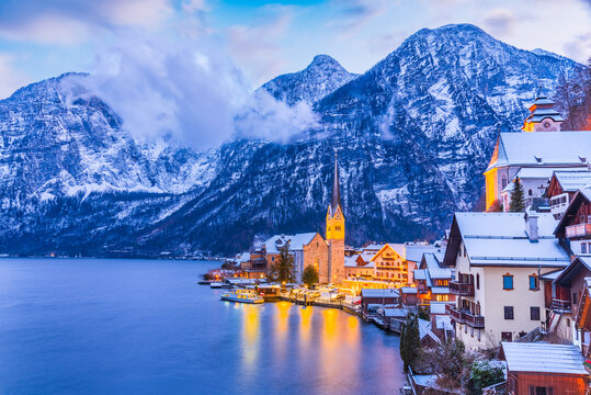 Hallstatt, Austria. Serene Alpine village with snow-covered rooftops on tranquil lake, breathtaking mountain backdrop winter twilight