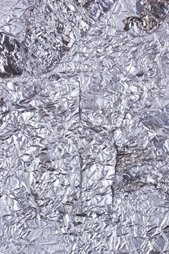 Shiny heavily wrinkled metal silver gray foil vertical texture background for design