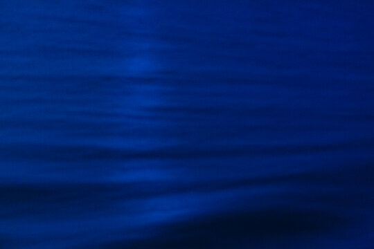 The ocean surface, midnight blue colours in the darkness, reflections and ripples on the water.