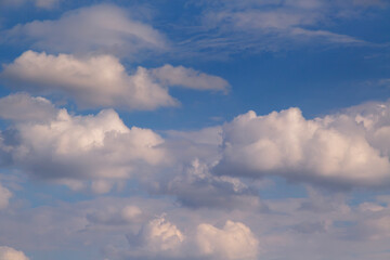 Layered white clouds with warm light drifting across a deep blue sky. © Александр Ланевский