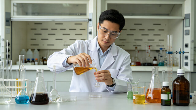 Asian Scientist Pouring Chemical Liquid In Modern Laboratory