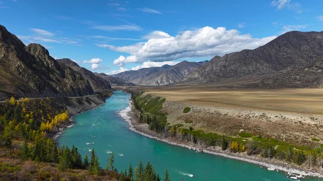 Romantic couple in vibrant outfits looking at mountain turquoise river valley.