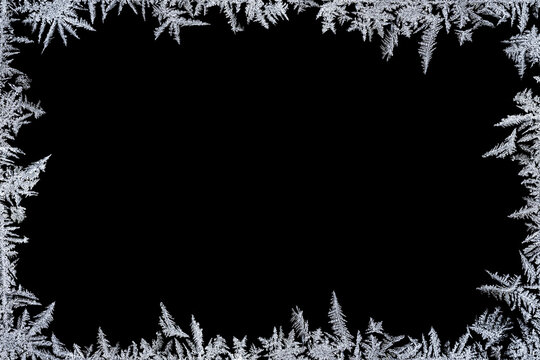 Frosty frame overlay. Frame of  frost crystals on a black background with copy space. Perfect for winter cards, invitations, posters, photos and seasonal designs.