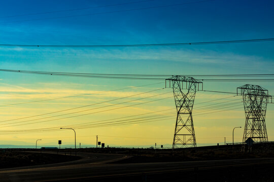High transmission towers and wires, a row of pylons and a sunset sky.