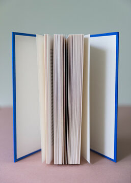 Close up of opened book with a hard blue cover, balanced upright
