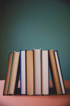 Row of old hardcover books, balancing upright on shelf