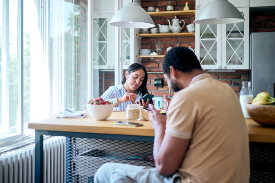 Couple ignoring each other while using smartphones at breakfast