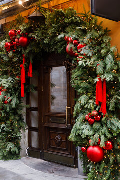 Grand Wooden Door Archway decorated with Pine Garlands, Warm Lights, and Glossy Red Baubles. Christmas street decor