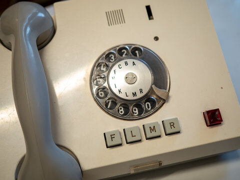 Vintage beige rotary dial telephone with a gray handset and function buttons. Close-up of a retro landline phone illustrating analog communication and telecommunications history.