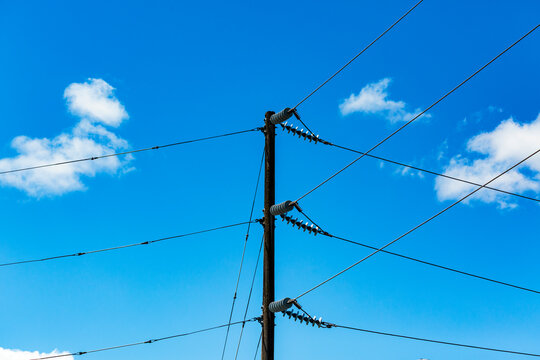 Telephone pole and wires, communication lines against a blue sky.