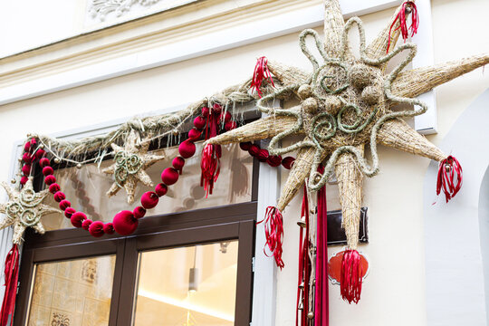 Large handmade Christmas straw star and red felt garland decorating street shop entrance. Traditional folk style Christmas facade decoration, festive holiday background