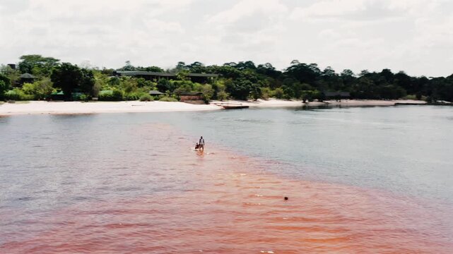 A person walking with their dog by the Red Lake in Canaima, Venezuela