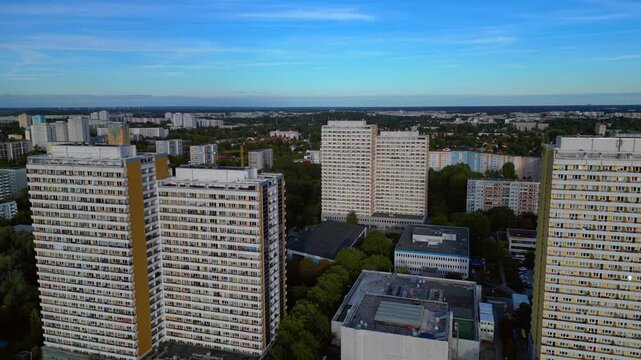 Marzahn district in Berlin featuring numerous high rise residential buildings surrounded by green areas under a clear sky. Gorgeous aerial view static hovering drone panorama
