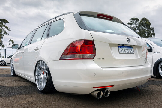 Rear view of a modified white Volkswagen Jetta Variant station wagon with slammed air suspension, dual exhaust pipes, and custom alloy wheels.