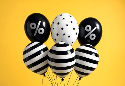 Five Black and White Balloons with Percentage and Star Designs Floating Together