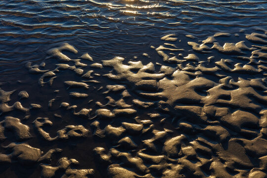 Beach sand formations, created by water action, ripples and ridges, patterns, shallow water and an incoming tide.