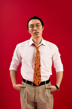 Young handsome Asian man in stylish attire expresses confidence against a vibrant background