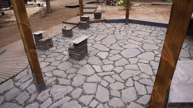 Newly installed crazy paving flagstone patio in a backyard landscaping project with wooden posts