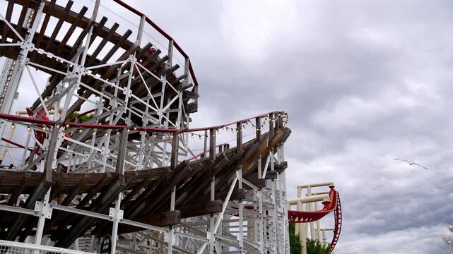 Roller coaster with grey sky in motion at amusement park.