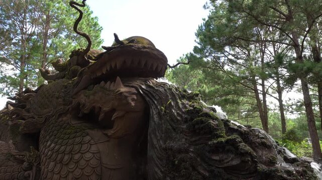 A carved dragon head stands among trees in Da Lat