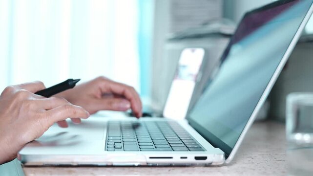 Close up of a person typing on a laptop keyboard, then reaching for a glass of water to drink during a work break at home, showing remote work, hydration and daily routine in a modern apartment.