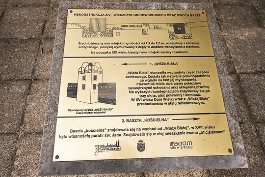 Historical information plaque about medieval city walls and towers in Radom, Poland mounted on stone pavement near tourist site