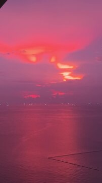 Peaceful sunset over the sea with distant boats and hazy sky in Pattaya, Thailand
