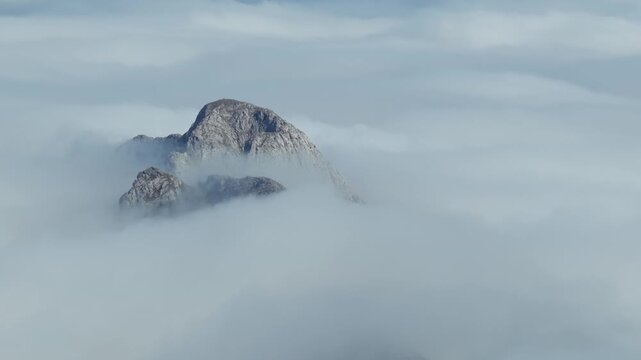 Aerial view of thick clouds rolling over limestone peaks and green valleys in Urkiola Natural Park, Basque Country, Spain