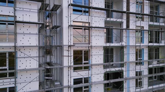 Building facade thermal insulation work with scaffolding on apartment house