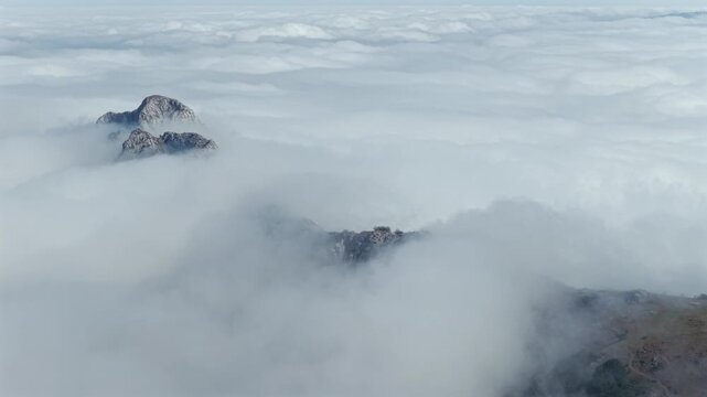 Aerial view of thick clouds rolling over limestone peaks and green valleys in Urkiola Natural Park, Basque Country, Spain