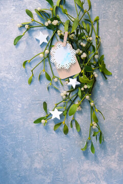 Christmas, New year holidays concept. beautiful mistletoe plant branch with paper card on blue-gray background. decor for Christmas, Advent, Yule, New year holidays, festive winter season. top view