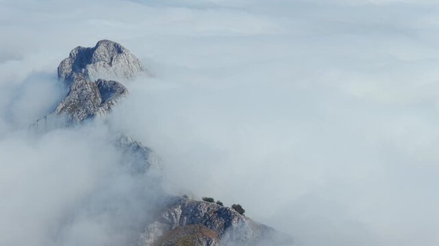 Aerial view of thick clouds rolling over limestone peaks and green valleys in Urkiola Natural Park, Basque Country, Spain