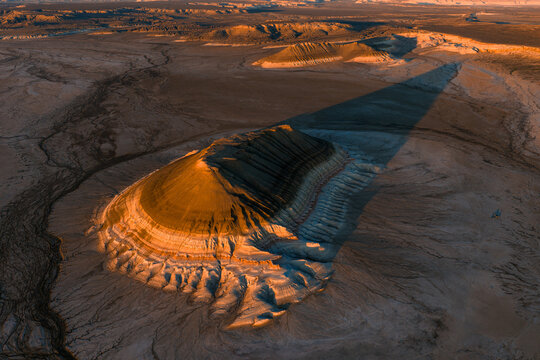 Aerial view of Gora Bokty featuring its unique striated rock formations and long shadows cast across the arid desert landscape in Karakiya District, Mangystau Region, Kazakhstan.