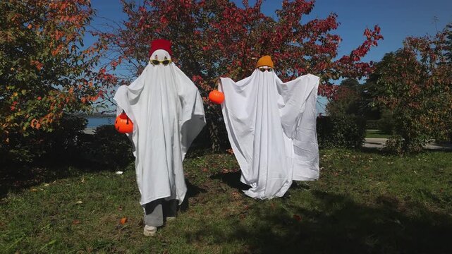 two kid in Halloween ghost costumes Wearing bright hats and black glasses,  in the park. Halloween party