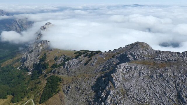Aerial view of thick clouds rolling over limestone peaks and green valleys in Urkiola Natural Park, Basque Country, Spain