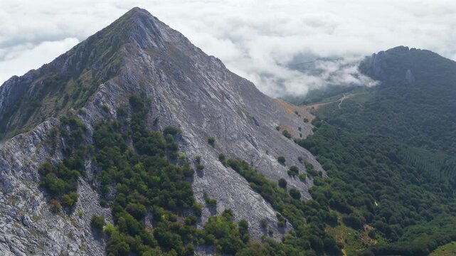 Aerial view of thick clouds rolling over limestone peaks and green valleys in Urkiola Natural Park, Basque Country, Spain