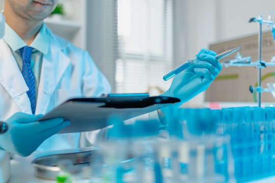 Scientist examining laboratory samples and test tubes for scientific research, analysis, and experimental studies in a modern laboratory.
