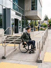 Obraz premium Young man using wheelchair outside public library with accessible entrance ramps representing inclusion accessibility independence education and community participation together